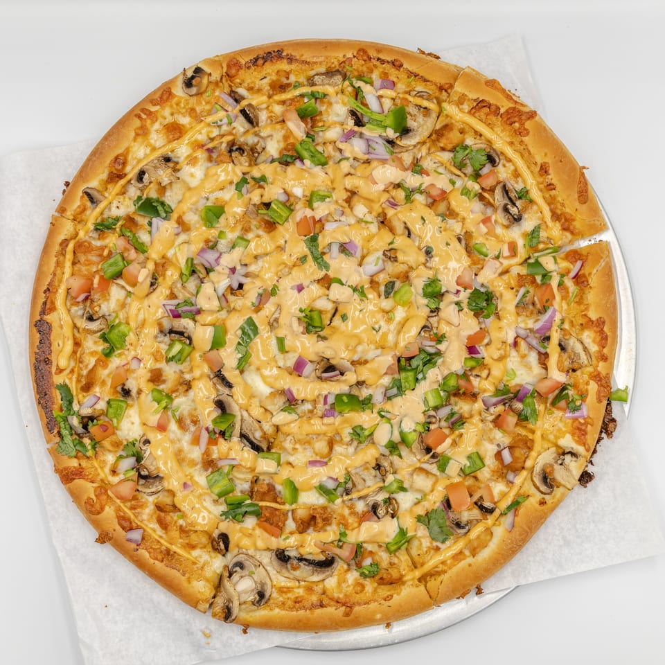 Large cheesy pizza topped with mushrooms, green peppers, tomatoes, red onions, cilantro, and drizzled orange sauce.